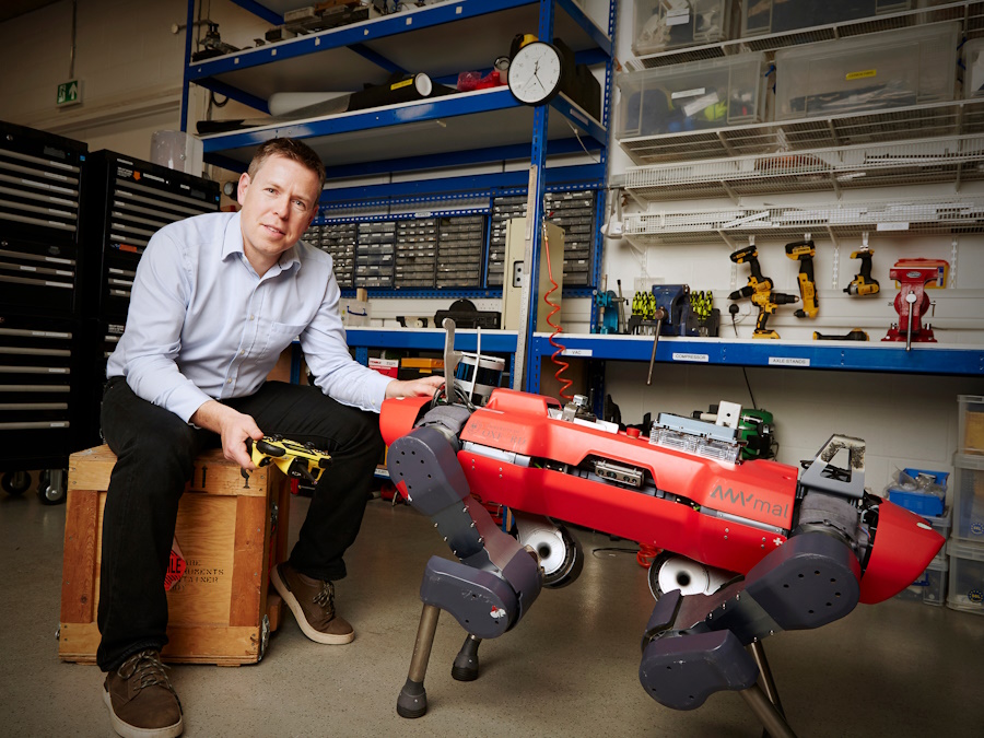 A man sitting on a box next to a robot